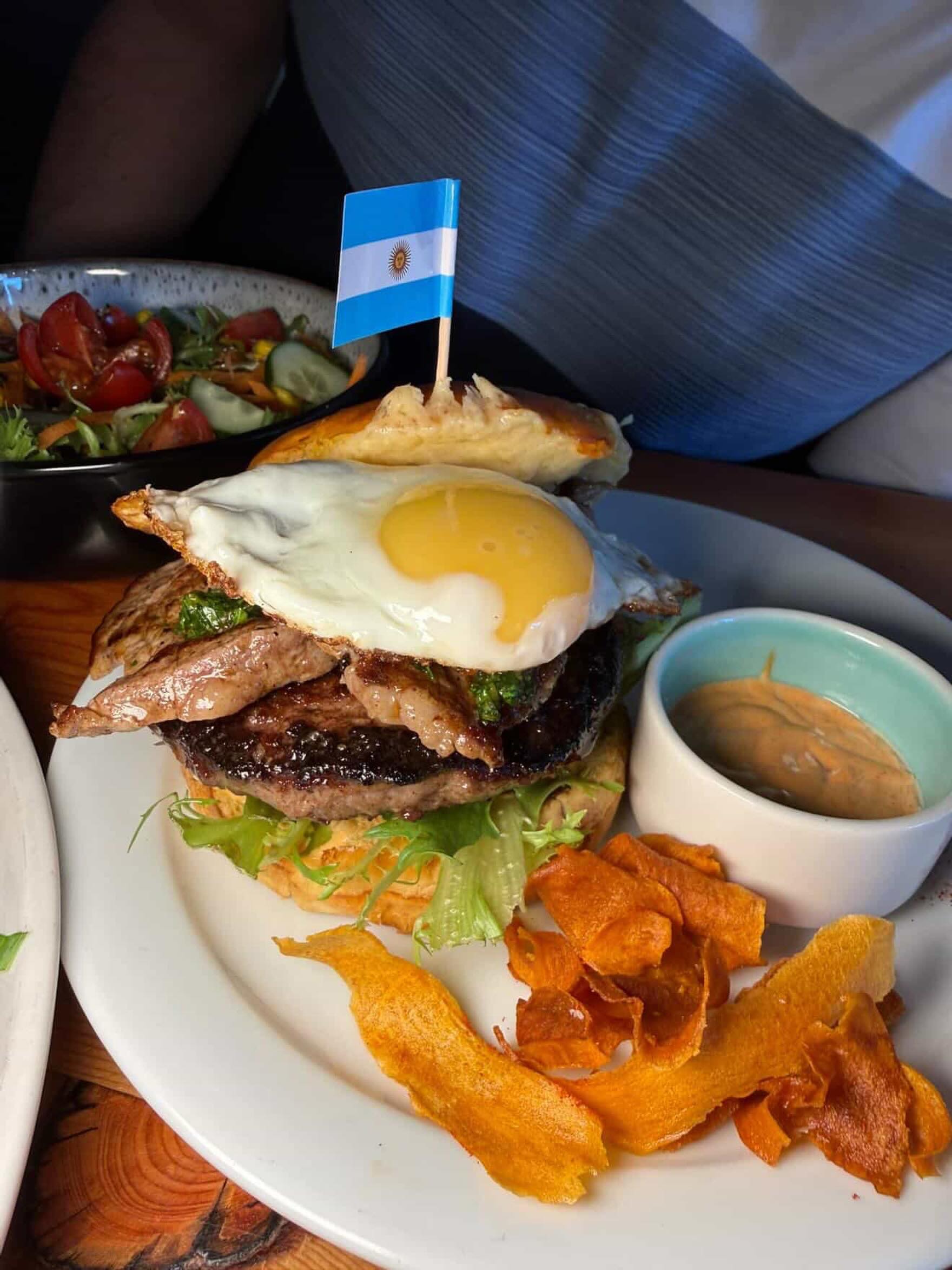 Stacked steak and fried egg with salad, dipping sauce and crisp sweet potato